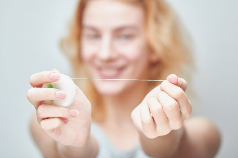 Frau mit Zahnseide in der Hand