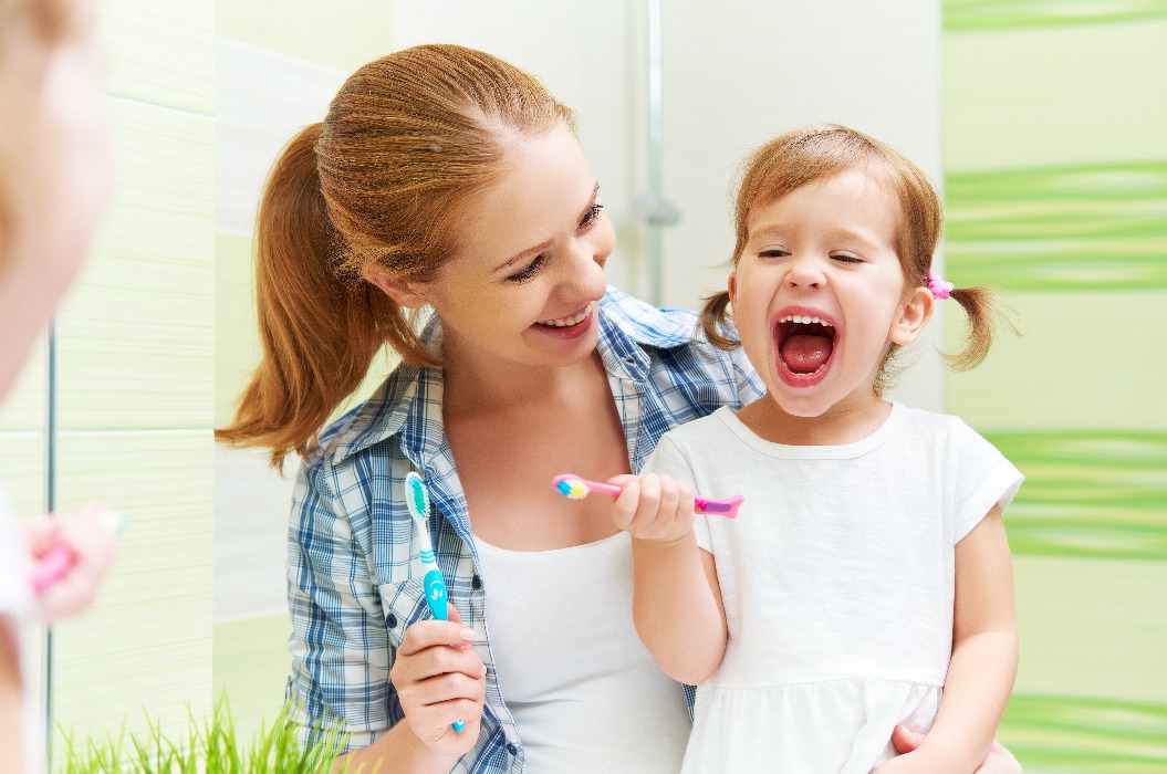 Mutter zeigt kleinen Tochter, wie man Zähne putzt