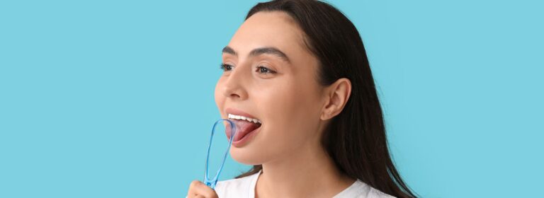 Eine junge Frau nutzt einen Zungenreiniger um ihre Zunge zu reinigen